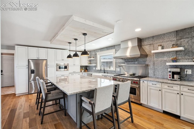 kitchen featuring wall chimney exhaust hood, light stone countertops, stainless steel appliances, light wood-style floors, and open shelves