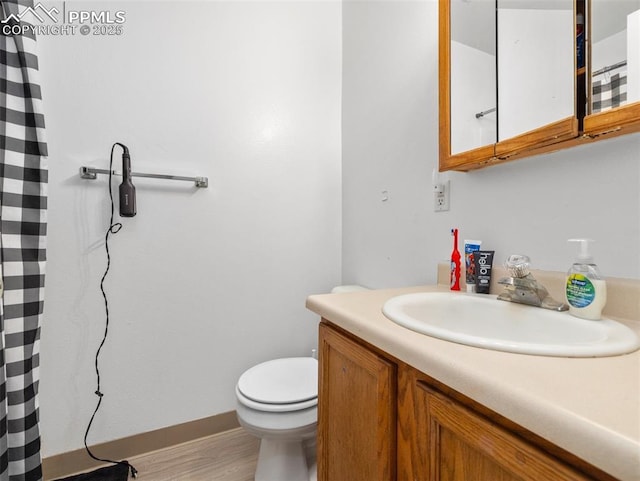 full bathroom with wood finished floors, vanity, toilet, and baseboards