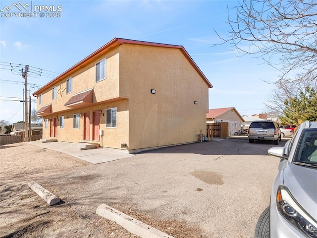 view of property exterior with entry steps, fence, and stucco siding