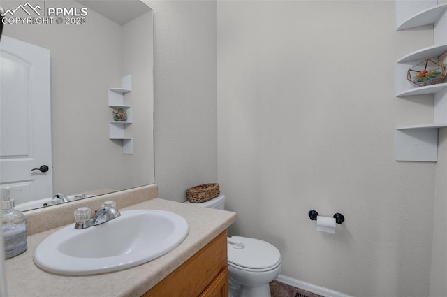 half bath featuring toilet, vanity, and baseboards