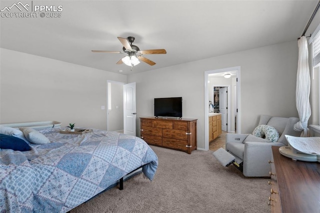 bedroom with a ceiling fan, light colored carpet, and ensuite bath