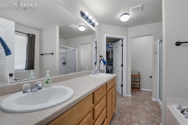 bathroom with a stall shower, a spacious closet, visible vents, and a sink