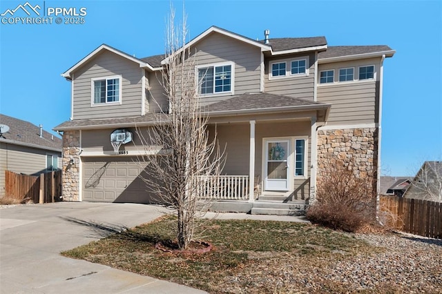 traditional-style home featuring an attached garage, covered porch, fence, stone siding, and concrete driveway