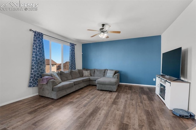 living room featuring ceiling fan, baseboards, and wood finished floors