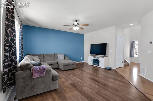 living area featuring visible vents, stairway, ceiling fan, wood finished floors, and baseboards