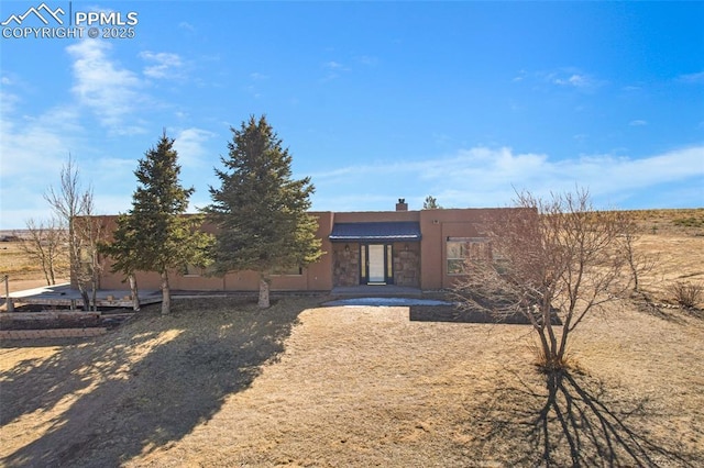 pueblo-style home with a chimney and stucco siding