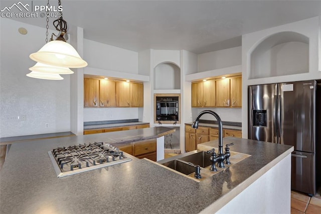 kitchen featuring stainless steel appliances, dark countertops, pendant lighting, and a sink