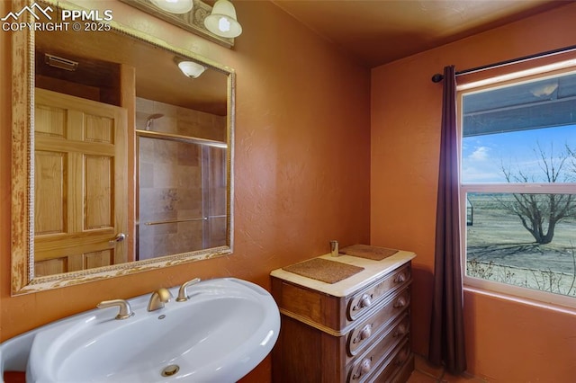 bathroom featuring an enclosed shower, a sink, and a textured wall