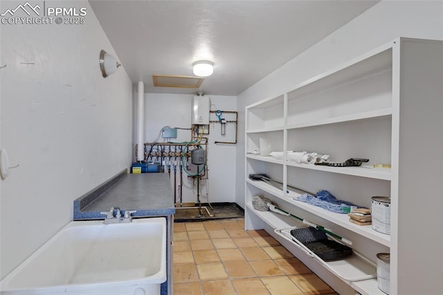 storage area featuring attic access, water heater, and a sink