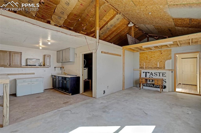 interior space with lofted ceiling, light countertops, and unfinished concrete flooring