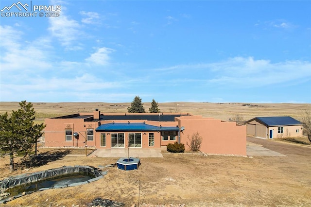 back of property with a patio, a hot tub, and stucco siding