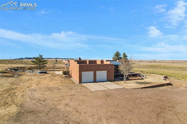 view of outdoor structure with a garage, driveway, and a rural view