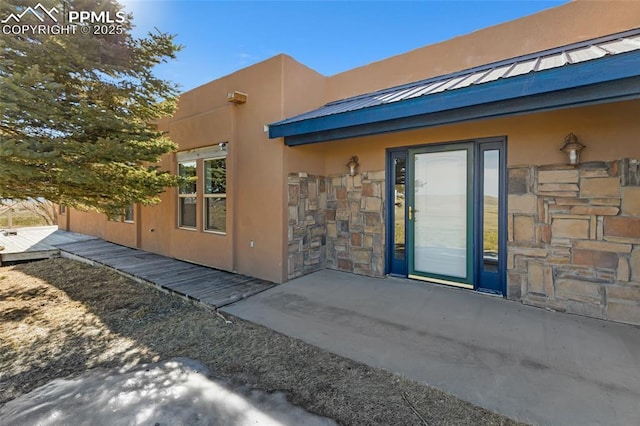 doorway to property with stone siding, metal roof, and stucco siding