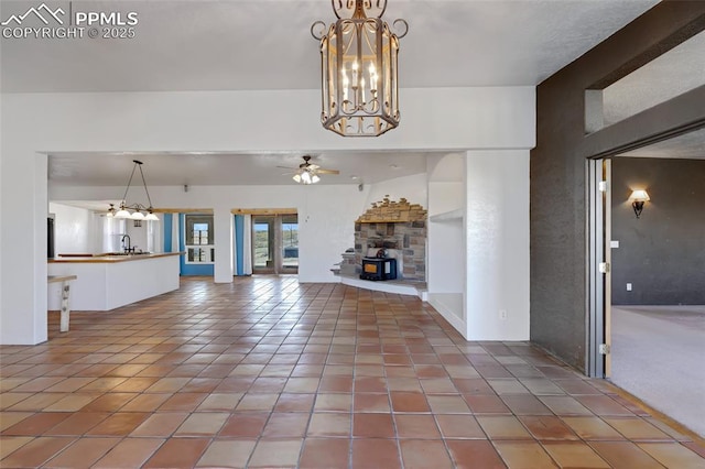 unfurnished living room with tile patterned floors, a sink, and ceiling fan with notable chandelier