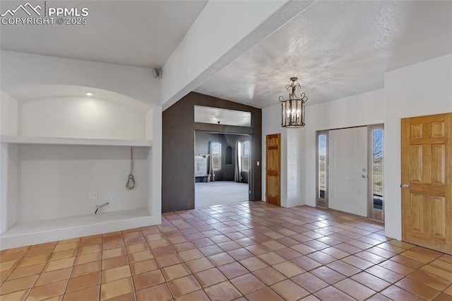 tiled foyer featuring a notable chandelier and a textured ceiling