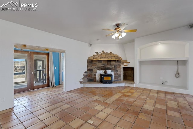 unfurnished living room featuring ceiling fan, built in features, french doors, tile patterned floors, and a wood stove