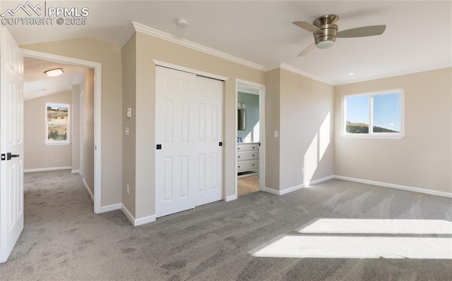 unfurnished bedroom featuring carpet flooring, multiple windows, crown molding, and baseboards