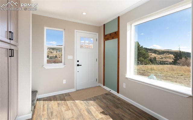 foyer entrance with recessed lighting, baseboards, crown molding, and wood finished floors