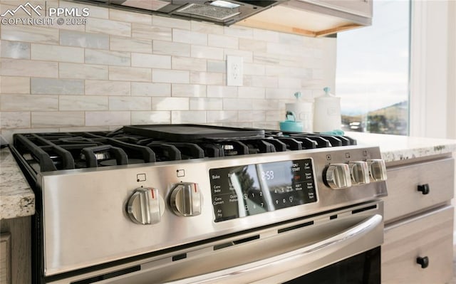 room details featuring stainless steel gas stove, backsplash, and light stone countertops