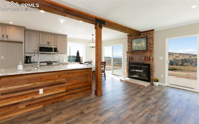 kitchen featuring stainless steel microwave, a brick fireplace, a wealth of natural light, decorative backsplash, and beamed ceiling