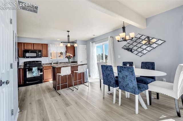 dining space featuring light wood-type flooring, an inviting chandelier, and beamed ceiling