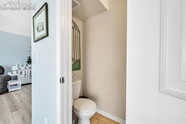 bathroom with toilet, wood finished floors, visible vents, and baseboards