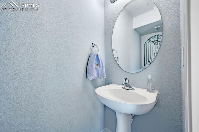 bathroom featuring visible vents and a textured wall