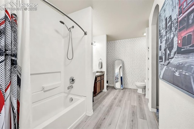 full bathroom featuring wallpapered walls, toilet, wood finished floors, tub / shower combination, and vanity