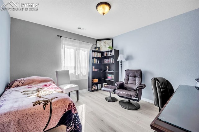 bedroom with visible vents, a textured wall, a textured ceiling, wood finished floors, and baseboards