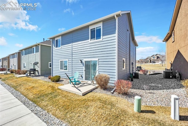 back of house with central air condition unit, a residential view, and a yard