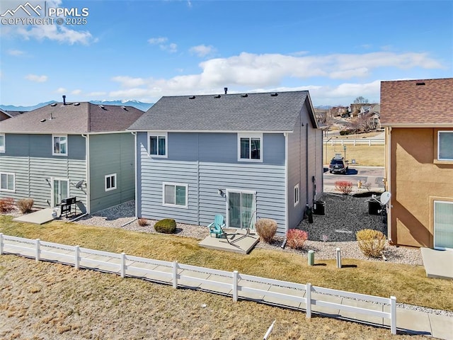 rear view of house featuring a shingled roof, fence private yard, and a patio