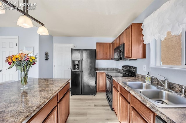 kitchen featuring brown cabinets, decorative light fixtures, dark countertops, a sink, and black appliances