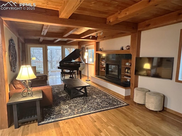 living area with a tiled fireplace, beamed ceiling, wooden ceiling, and wood finished floors