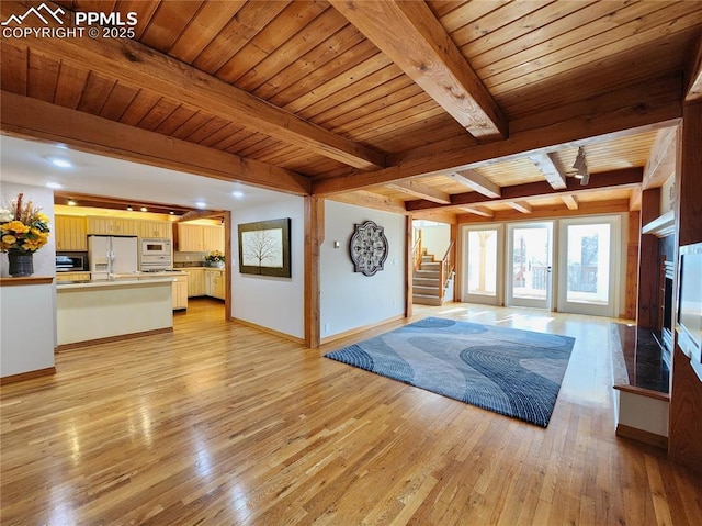 unfurnished living room with stairway, light wood-style flooring, wood ceiling, and baseboards