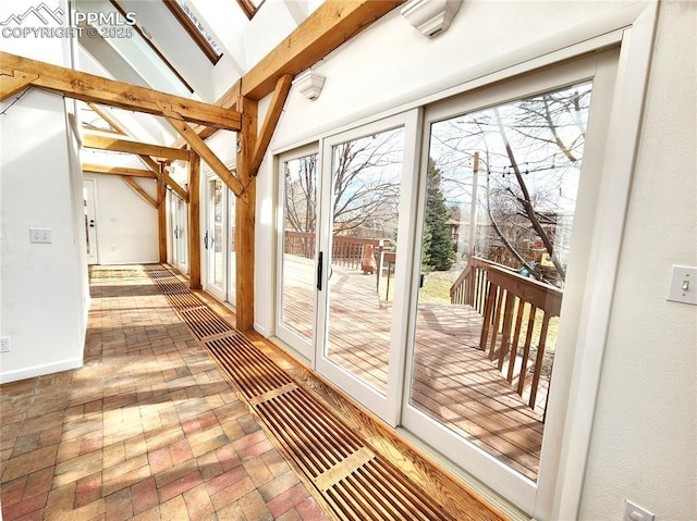 doorway to outside featuring plenty of natural light, vaulted ceiling with beams, and brick floor