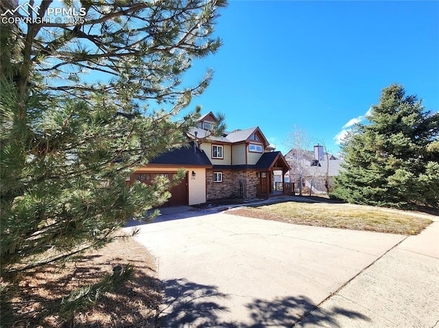 view of front of property with stone siding, concrete driveway, and a front yard