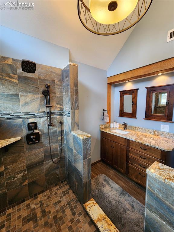 bathroom with vanity, lofted ceiling, wood finished floors, and walk in shower