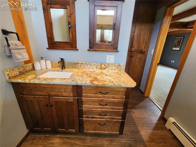 bathroom with vanity, wood finished floors, baseboards, and baseboard heating