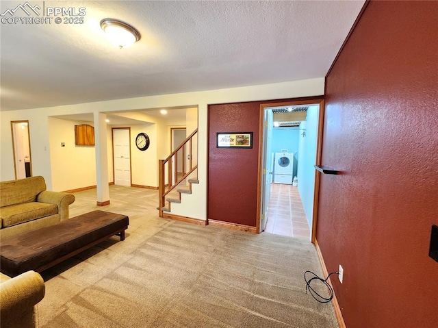 living area with baseboards, stairway, light carpet, washer and dryer, and a textured ceiling