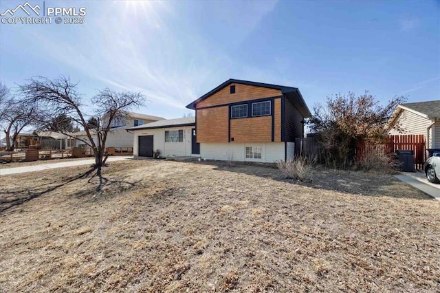 split level home featuring an attached garage and fence