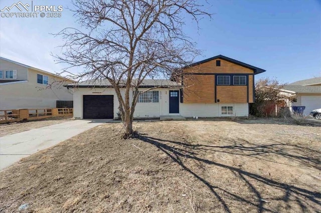 tri-level home featuring an attached garage, fence, and concrete driveway