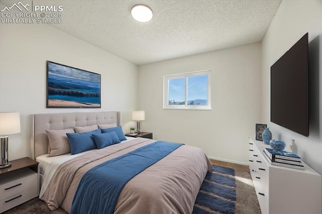 bedroom featuring baseboards, dark carpet, and a textured ceiling