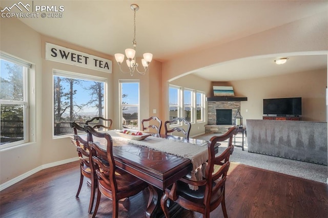 dining area with baseboards, a notable chandelier, dark wood finished floors, and a fireplace