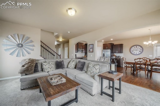 living room with baseboards, light wood finished floors, arched walkways, stairs, and a chandelier