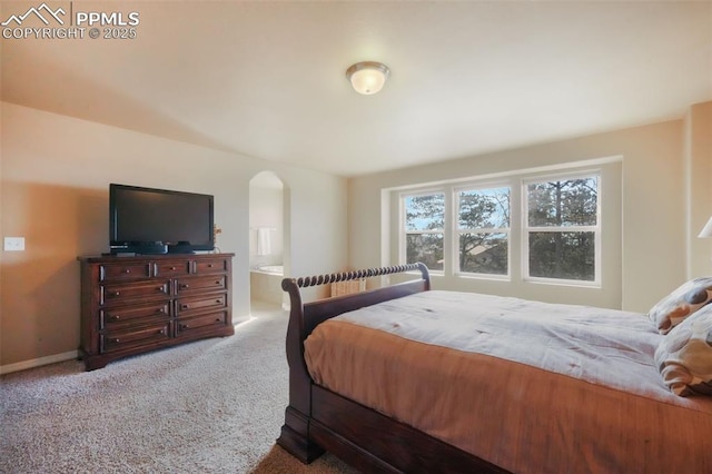 bedroom with baseboards, arched walkways, carpet floors, and ensuite bath