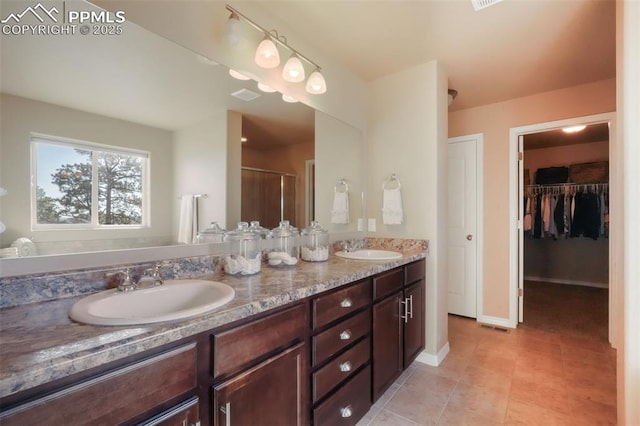 bathroom with double vanity, a stall shower, visible vents, and a sink