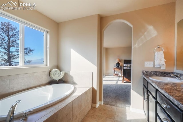 bathroom with tile patterned flooring, a garden tub, vanity, and baseboards