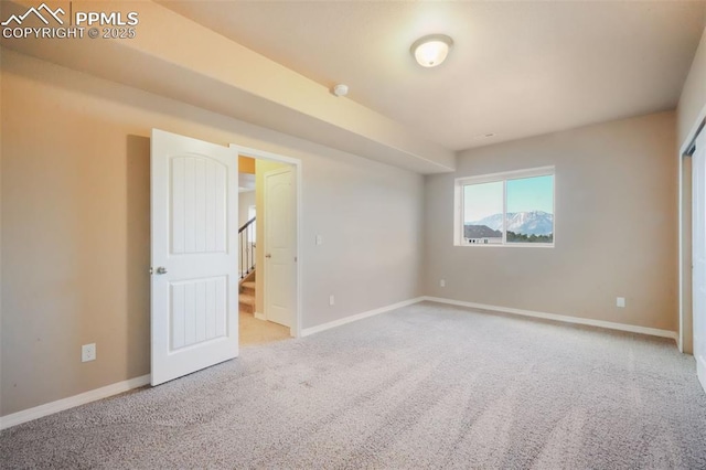 carpeted spare room with stairway and baseboards