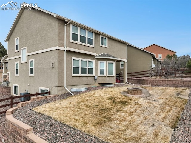 back of house with stucco siding, a fire pit, and fence