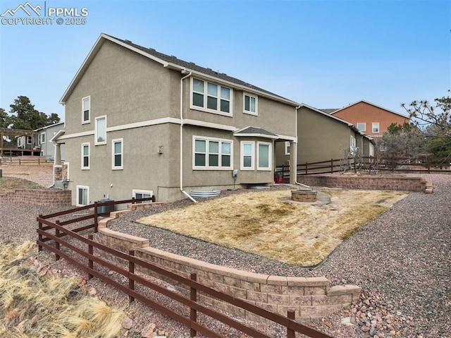 view of front facade featuring an outdoor fire pit, fence, and stucco siding